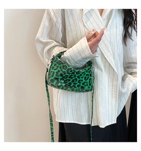 Detail of green leopard print patent saddle bag with silver buckle and adjustable strap