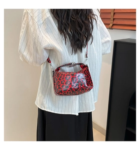 Close-up of glossy red and black leopard print handbag with silver hardware details