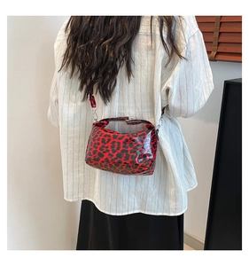 Close-up of red and black leopard print shoulder bag with glossy finish and metal buckles