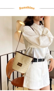 Detail of a beige woven bucket bag with brown leather trim and SpeedMai logo patch