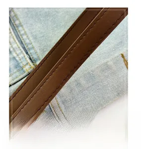 Detail of a brown leather shoulder strap with neat double stitching on denim fabric