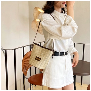 Detail showing woven texture and dark brown leather strap of the bucket bag