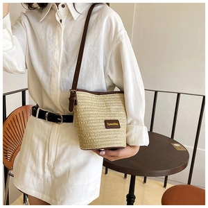 Detailed view of woven straw bucket bag with leather trim and adjustable shoulder strap