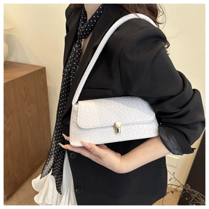 Detailed shot of a white woven shoulder bag with gold metal buckle on a model