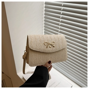 Detail of beige woven crossbody bag featuring a golden bow buckle and wave texture