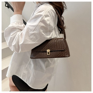 Détail d'un sac à bandoulière marron tressé avec boucle dorée et lanière assortie