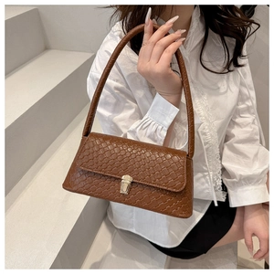 Close-up of caramel brown woven leather texture with gold metal buckle on small square bag