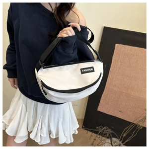 Close-up of white canvas crossbody bag with adjustable strap and fashion label detail
