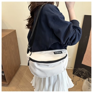Detail of a white minimalist canvas saddle bag with black straps and fashion woven label