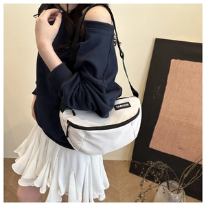 Close-up of white crossbody saddle bag with black strap and fashion label on model