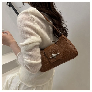 Close-up of brown woven underarm bag with silver star buckle worn by a model