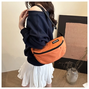 Detail view of the orange nylon saddle bag with a white FASHION logo and black strap