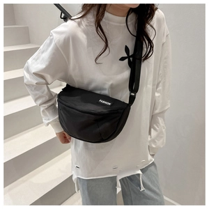 Detail of black crescent crossbody bag with FASHION label and adjustable nylon strap