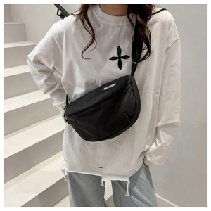 Detailed view of the black canvas crescent bag featuring a white fashion woven label