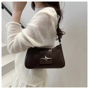 Detail of dark brown faux-crocodile texture shoulder bag with star metal buckle on white background