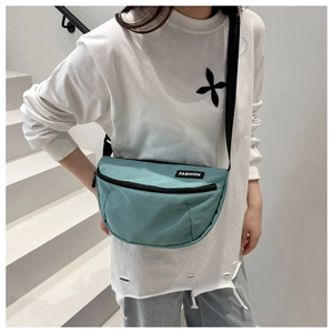 Detail view of mint green nylon crescent bag showing FASHION logo and crossbody fit
