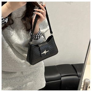 Detail of black woven underarm bag with silver cross star buckle on a model