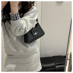 Side view of a black woven leather shoulder bag worn by a model in a minimalist setting