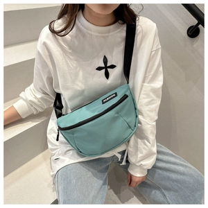Detail of mint green crescent nylon crossbody bag with black zipper and fashion label
