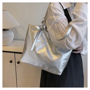 Detail of silver metallic tote bag with glossy wrinkled texture on model's shoulder