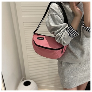 Detail of pink nylon crescent crossbody bag featuring fashion label and black strap