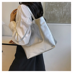 Detailed view of large silver metallic tote bag with sleek shoulder straps and wavy texture
