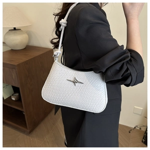 Detail of white woven underarm bag with silver cross star and knotted shoulder strap