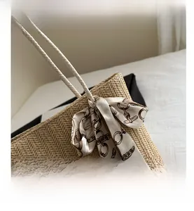 Detail of hand-woven straw tote with elegant beige silk scarf and gold chain pattern