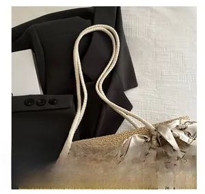 Detail of straw woven tote bag featuring white rope handles and silk scarf accent