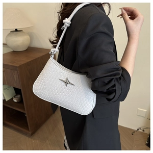 Detail of white woven underarm bag with metal cross star logo and knotted shoulder strap