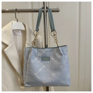 Detail of light blue nylon tote bag with floral embroidery and diamond quilted pattern