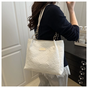 Detail showing the off-white quilted texture and gold chain strap of this shoulder tote bag