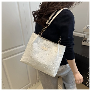 Detail view of large white tote bag with geometric texture and metal chain strap