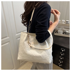 Detail of white jacquard tote bag with leather chain strap and woven texture on model