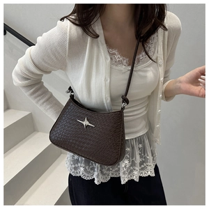 Detail of dark brown crocodile embossed crossbody bag with silver star-shaped metal buckle