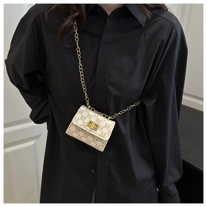 Detail of monogram mini crossbody bag with gold chain strap and twist lock on black fabric