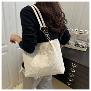 Detail view of large white jacquard tote bag with stylish gold metal ring chain