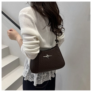 Detail of dark brown woven texture shoulder bag with a silver star metal ornament