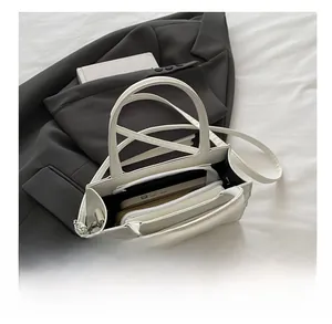 Vue détaillée de l'intérieur d'un sac à main blanc texturé avec plusieurs compartiments