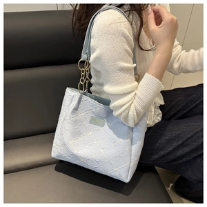 Close-up of light blue tote bag featuring diamond quilted stitching and gold chain strap