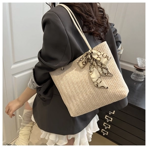 Detail of straw woven tote bag featuring a decorative vintage chain print silk scarf