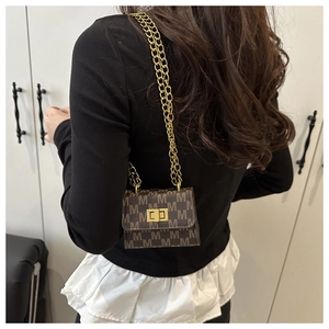 Detailed view of mini square crossbody bag with M-pattern and gold chain strap