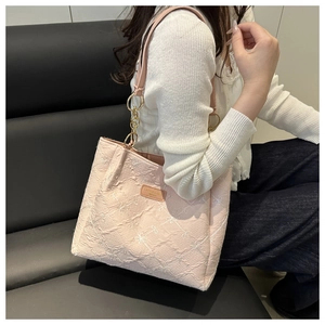 Detail of pink embroidered tote bag showing floral texture and metallic strap links