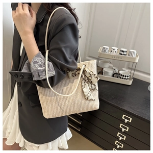 Detail of hand-woven straw tote bag featuring chic silk scarf handle and chevron pattern