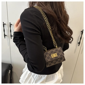 Detail of a brown flap bag with M-letter pattern and golden metal chain strap