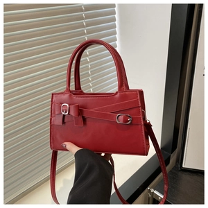 Détail du sac à main rouge avec nœud papillon, boucle argentée et similicuir texturé