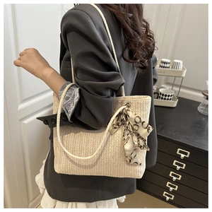 Close-up of straw woven tote bag with cotton rope handles and decorative silk scarf