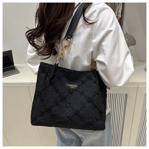 Detail of black quilted tote bag with silver sequins and metallic brand tag