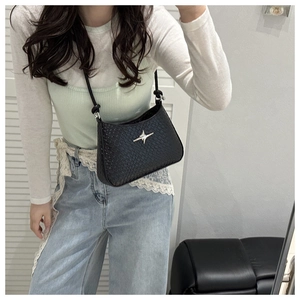 Detail of black textured crossbody bag with silver star buckle and woven pattern