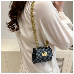 Detail view of mini black flap bag with gray M pattern and gold chain on model